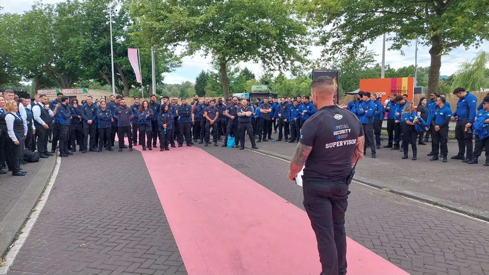 Supervisor van SSG met portofoon kijkt uit over een volgepakt festivalterrein